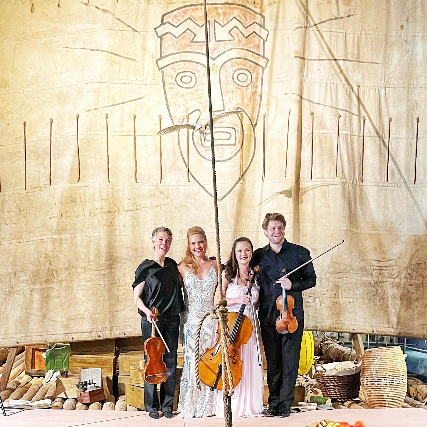 Ida Bryhn, Julie Coucheron, Sandra Lied Haga and David Coucheron with instruments in front of the Kon-Tiki sail with the Kon-Tiki logo